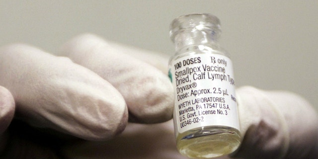 A vile of the smallpox vaccine that is being provided for the military is held up by a health worker.