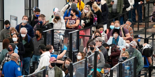 Passengers queue up to pass through the north security checkpoint Monday, Jan. 3, 2022, in the main terminal of Denver International Airport in Denver.