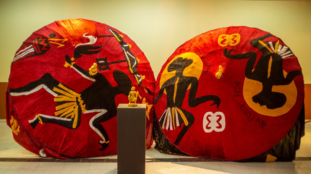 Two large red umbrellas emblazoned with black silhouettes decorated with gold accents.