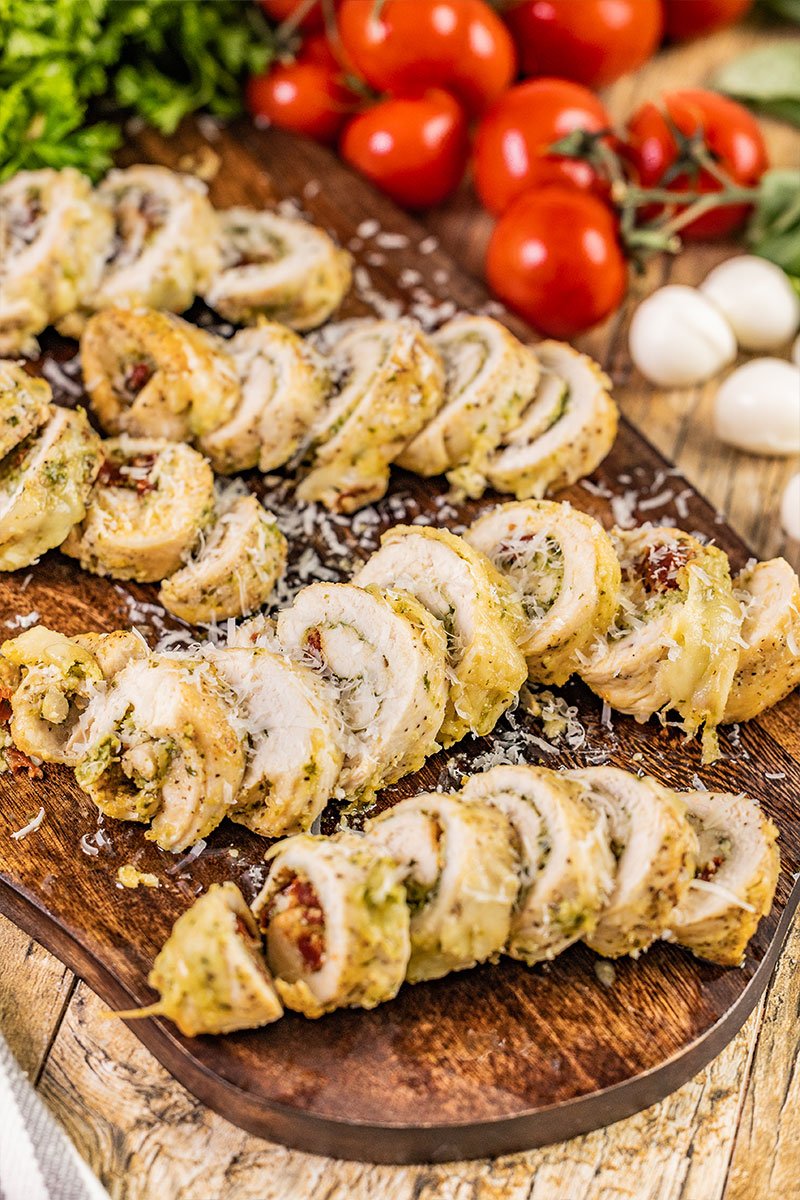 Chicken pesto roll ups on a serving board.