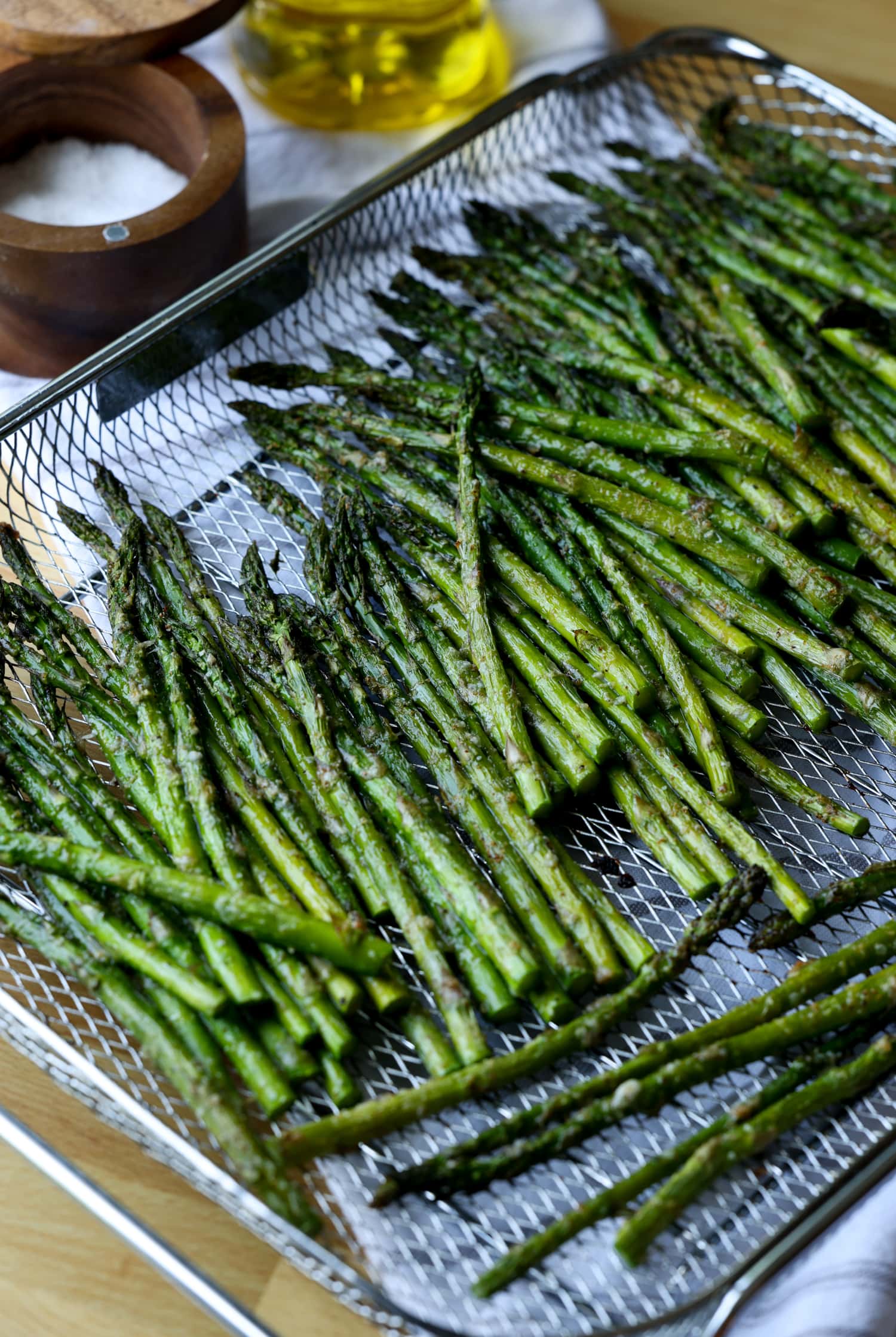 Make perfectly roasted Air Fryer Asparagus with Parmesan in 15 minutes! A healthy side dish that cooks up fast and easy in the air fryer. Air fryer asparagus spears spread out over a mesh cooling rack.