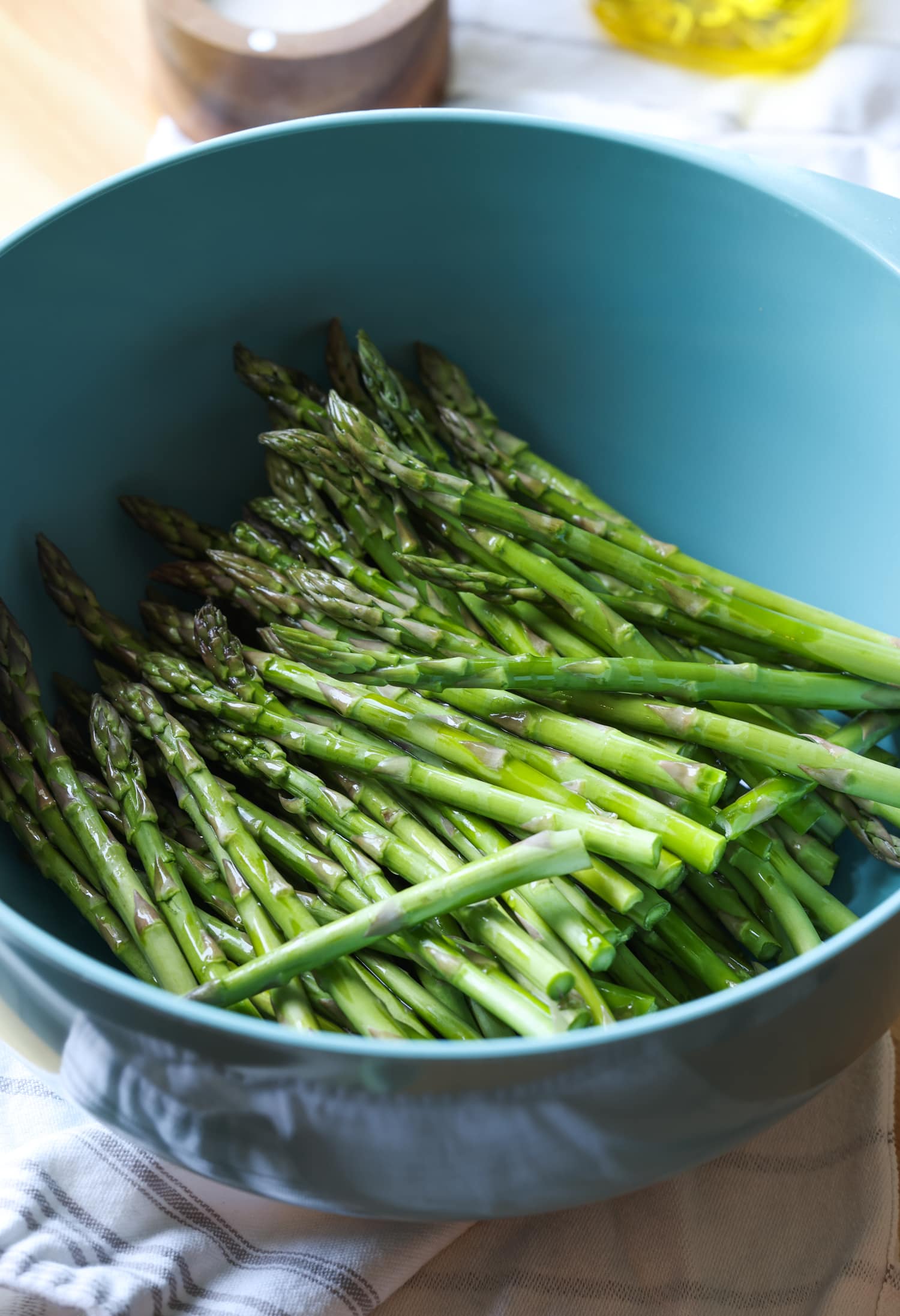 Make perfectly roasted Air Fryer Asparagus with Parmesan in 15 minutes! A healthy side dish that cooks up fast and easy in the air fryer. Asparagus spears in a large blue bowl.
