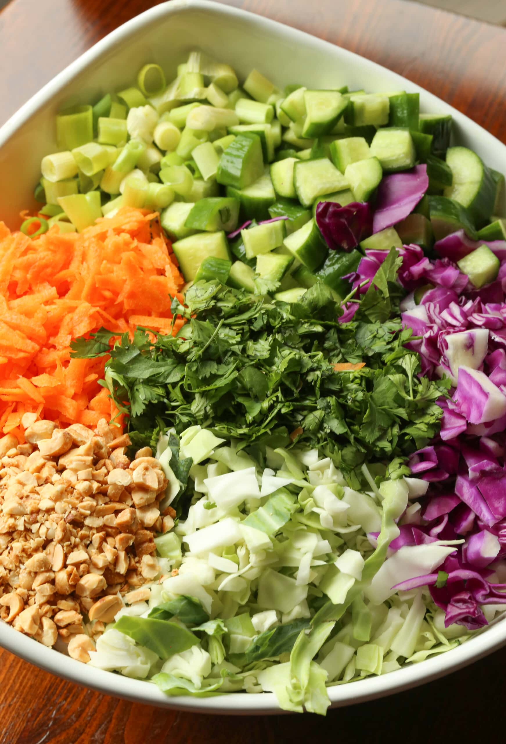 Eat the rainbow with this Rainbow Crunch Cabbage Salad tossed in deliciously spicy Thai-style peanut dressing! A fresh and easy side dish. The ingredients for rainbow crunch salad combined in a bowl.